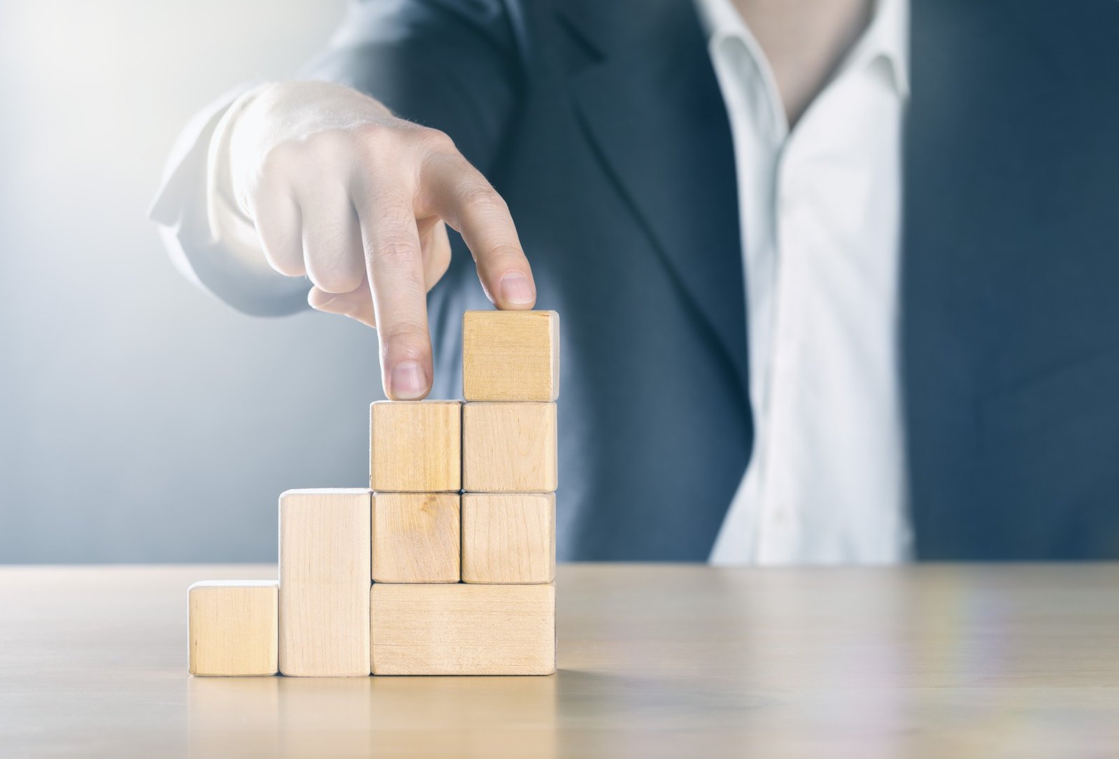 Hand stacking wooden blocks to represent structured growth and change delivery